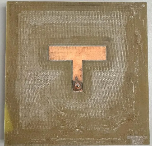 The manufactured antenna: a square board with the copper T-shaped patch left standing in a milled pocket, and the SMA probe feed near the bottom of the stem.