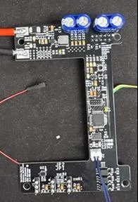 Figure 6: the second prototype, a black U-shaped board with battery leads and capacitors fitted.