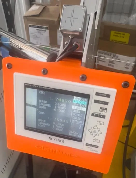 Photo from the plant: the orange printed mount holding the Keyence display on the stand.